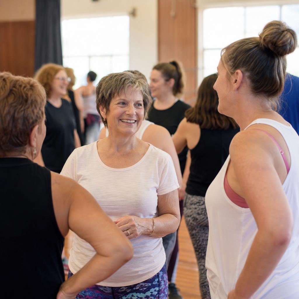 Inclusive dance fitness class with participants chatting and smiling together